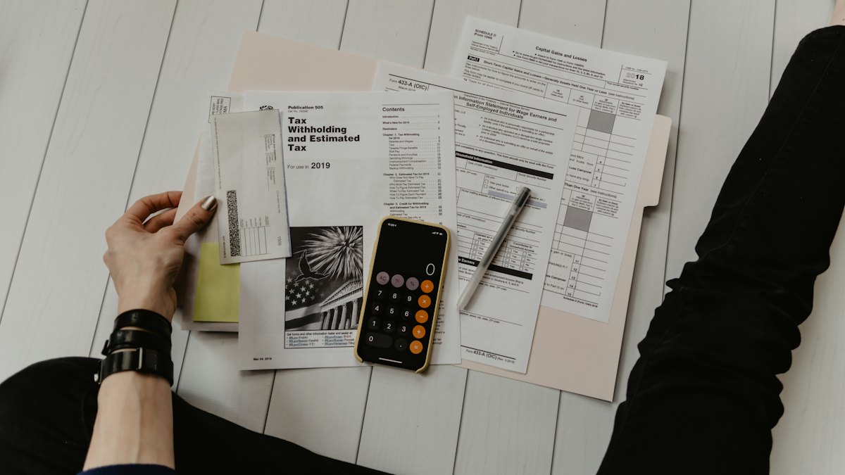 Hands working through paperwork with a calculator and a phone