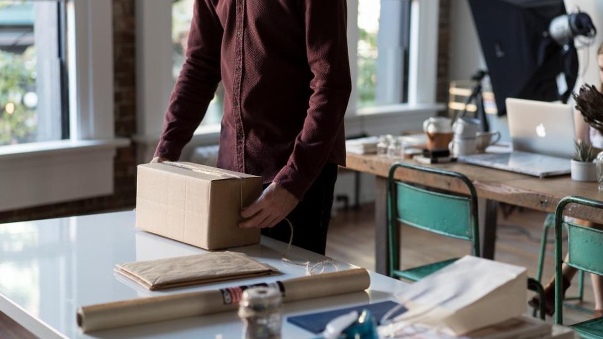 Person packing a cardboard box on a desk